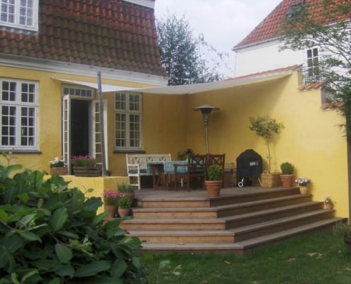 Havesejl monteret på gult hus.